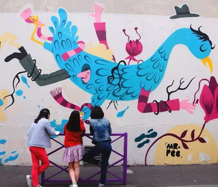 Children solving riddles in front of a colorful street art mural in Paris