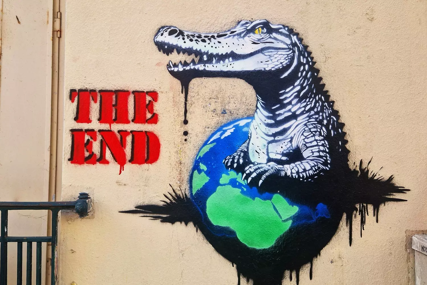 Stencil of a crocodile devouring the Earth, with the words The End in red