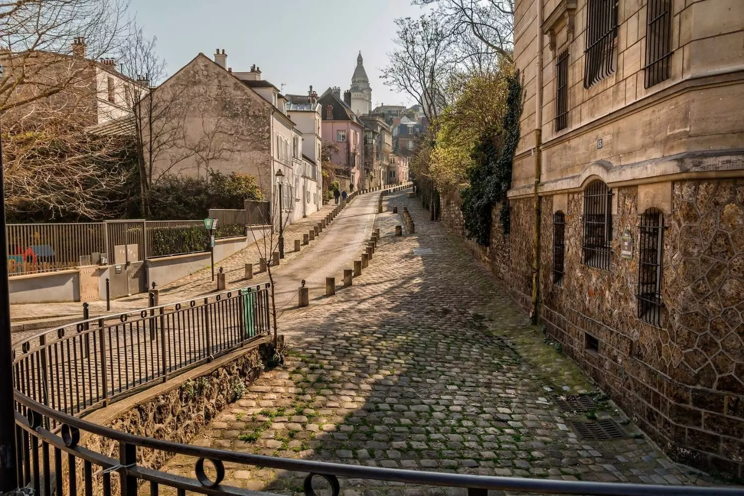 Sloping cobbled lane in Montmartre lined with railings and old houses