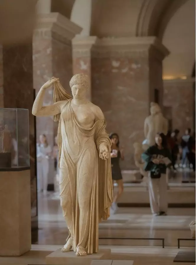 Statue antique en marbre d'une déesse drapée, dans une galerie de sculptures du Louvre