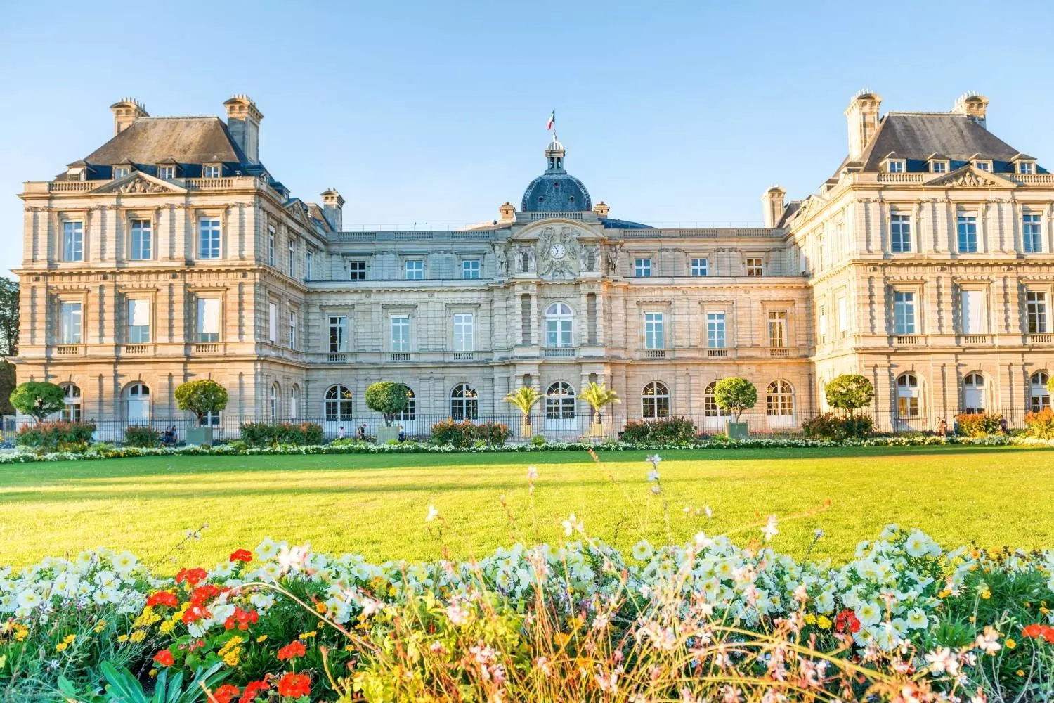Le palais du Luxembourg derrière la pelouse et les massifs fleuris du jardin