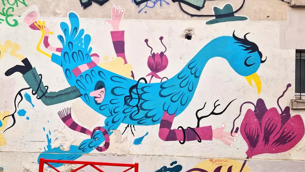 Fresque colorée d'un grand oiseau bleu entouré de personnages, sur un mur de Belleville