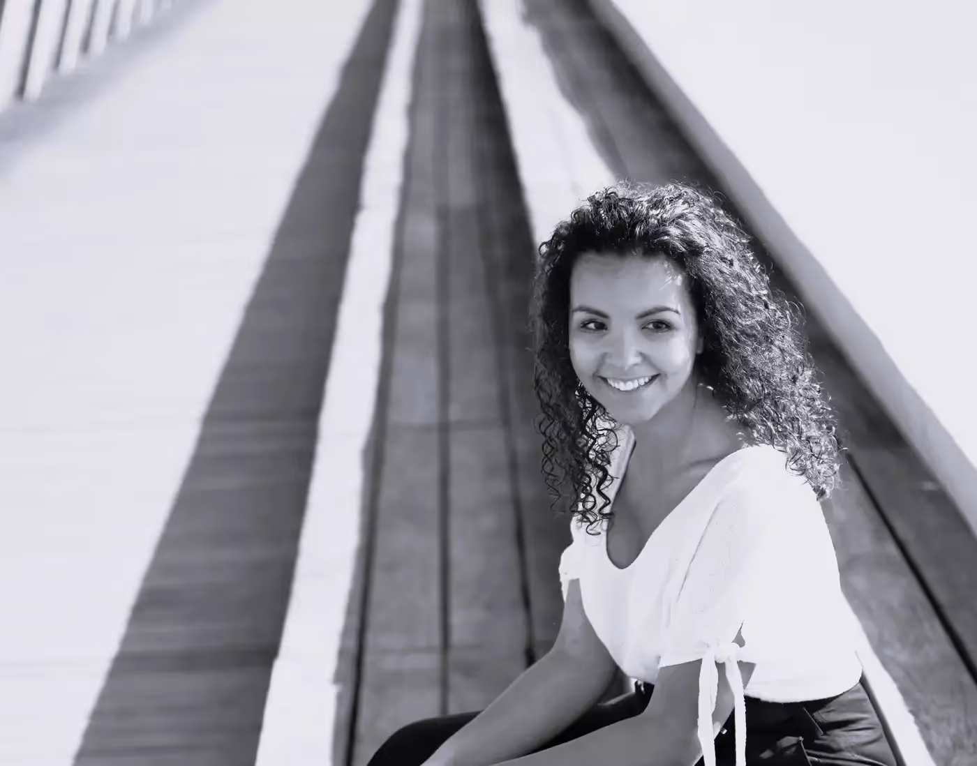 Portrait en noir et blanc de Camille, guide aux cheveux bouclés, souriante