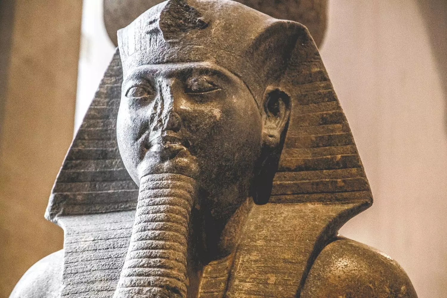 Visage d'une statue de pharaon coiffé du némès et portant la barbe postiche, au Louvre