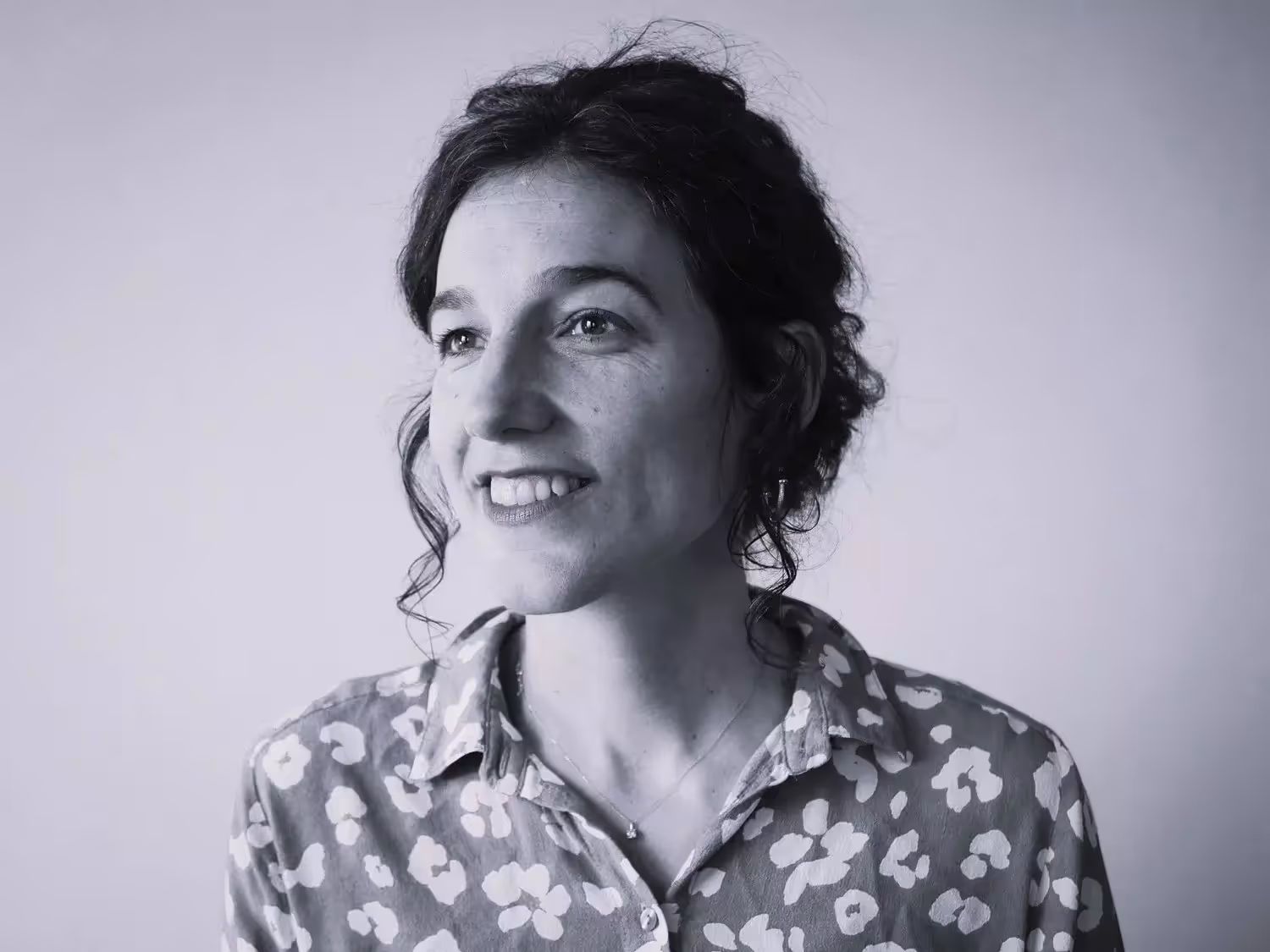 Portrait en noir et blanc de Mathilde, guide, souriante en chemise à motifs