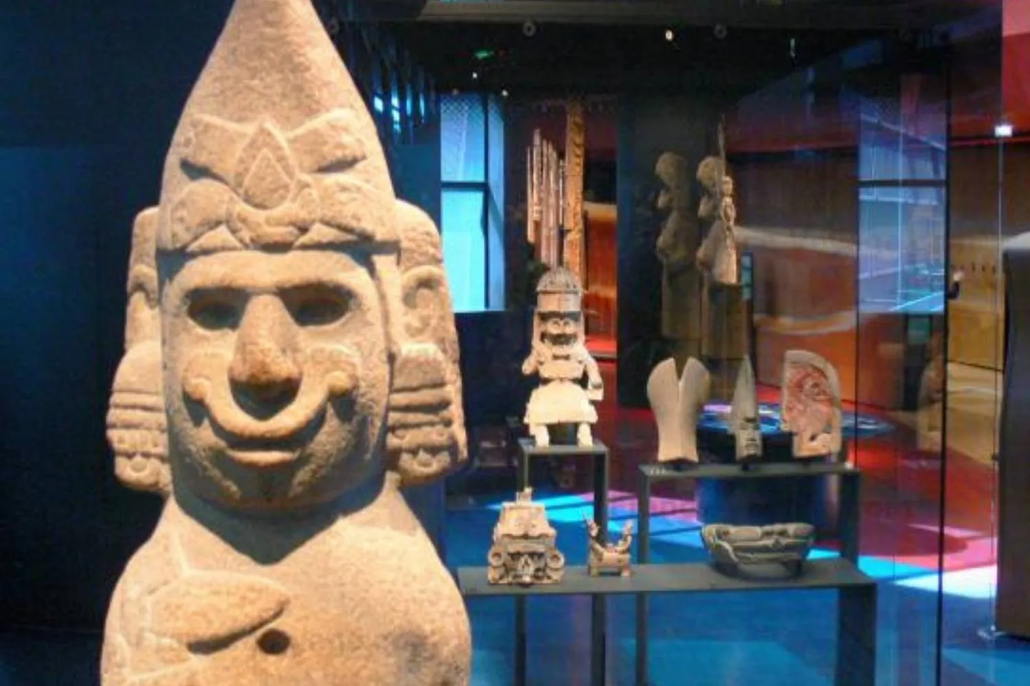 Sculpture de pierre au visage souriant et vitrines d'objets anciens au musée du quai Branly