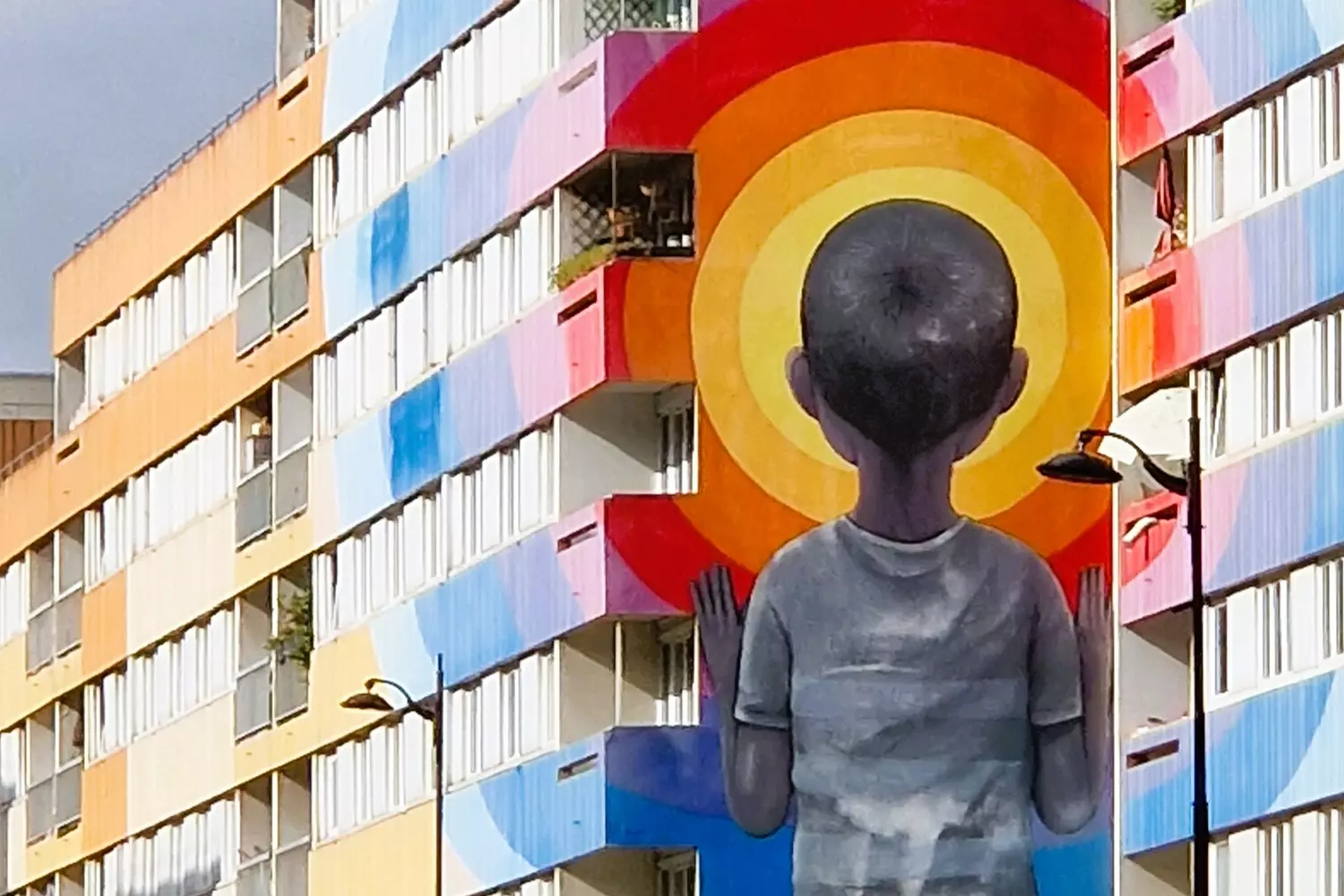 Fresque géante d'un enfant vu de dos devant un soleil orange, sur un immeuble du 13e arrondissement